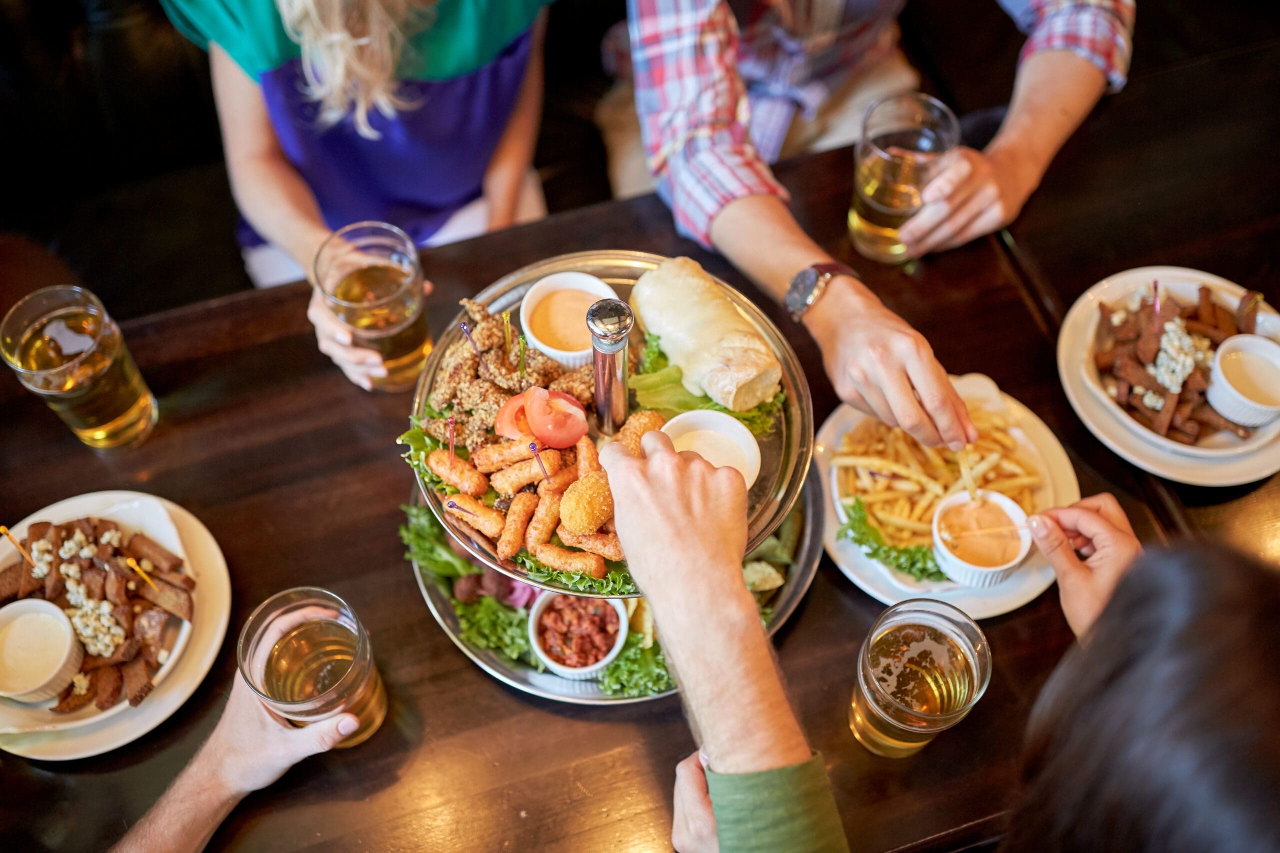 Friends eating appetizers and drinking at a bar or pub