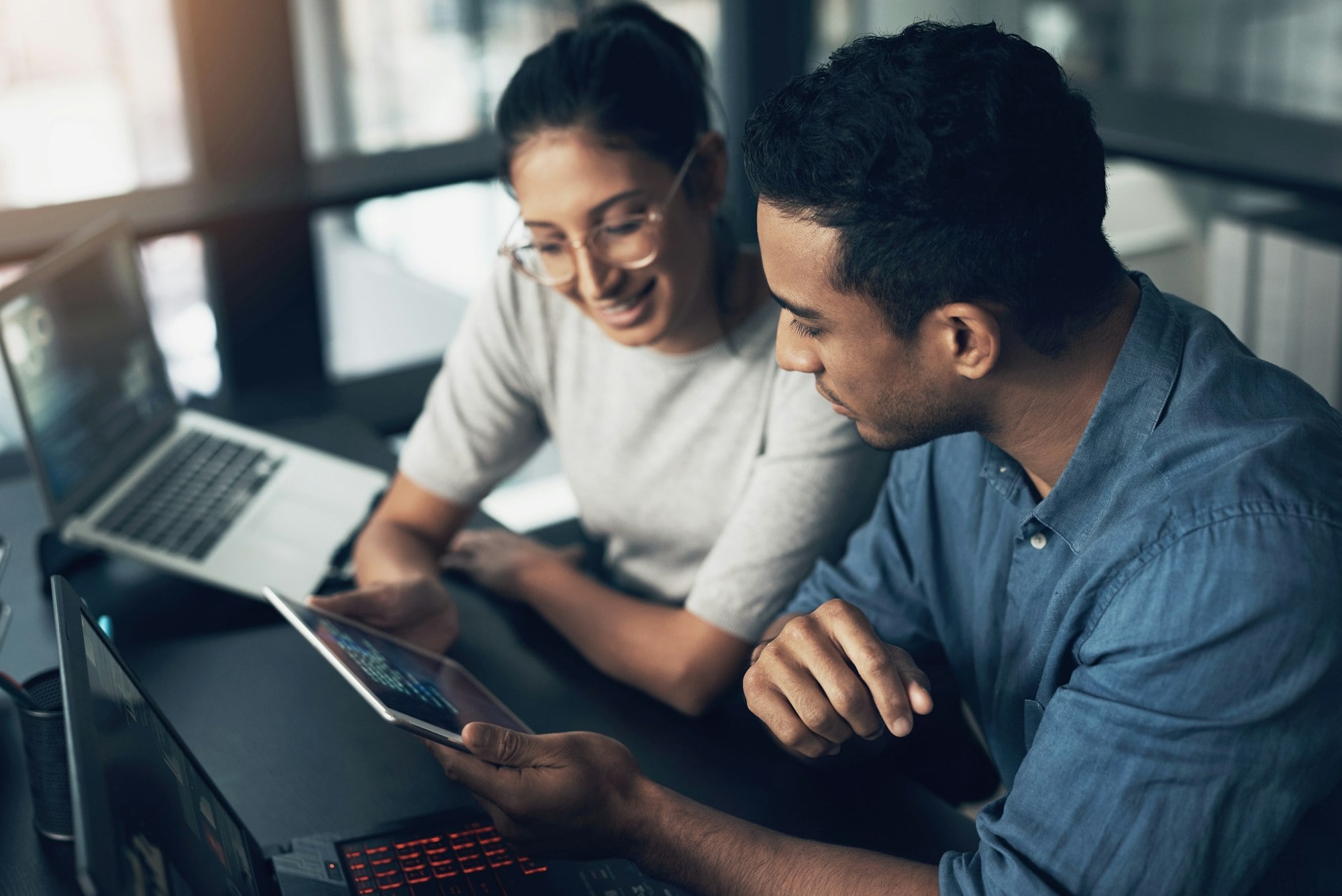 Two young workers using a digital tablet in a modern office